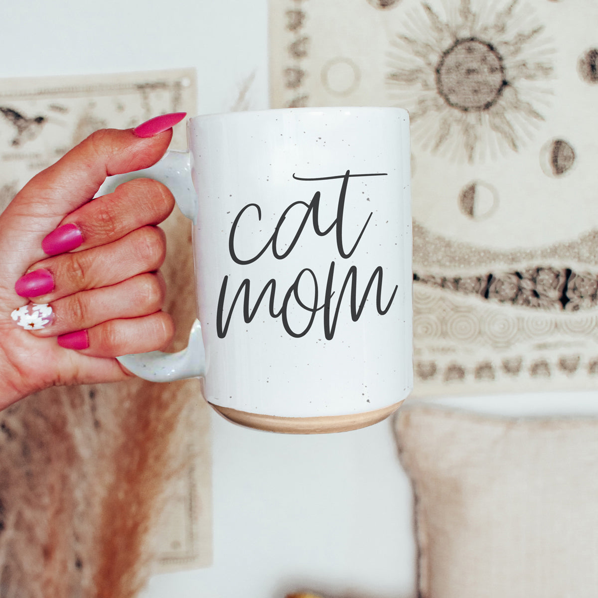 A stylish off-white ceramic mug with dark speckles, featuring a black graphic that reads 'Cat Mom' on both sides, perfect for cat lovers.