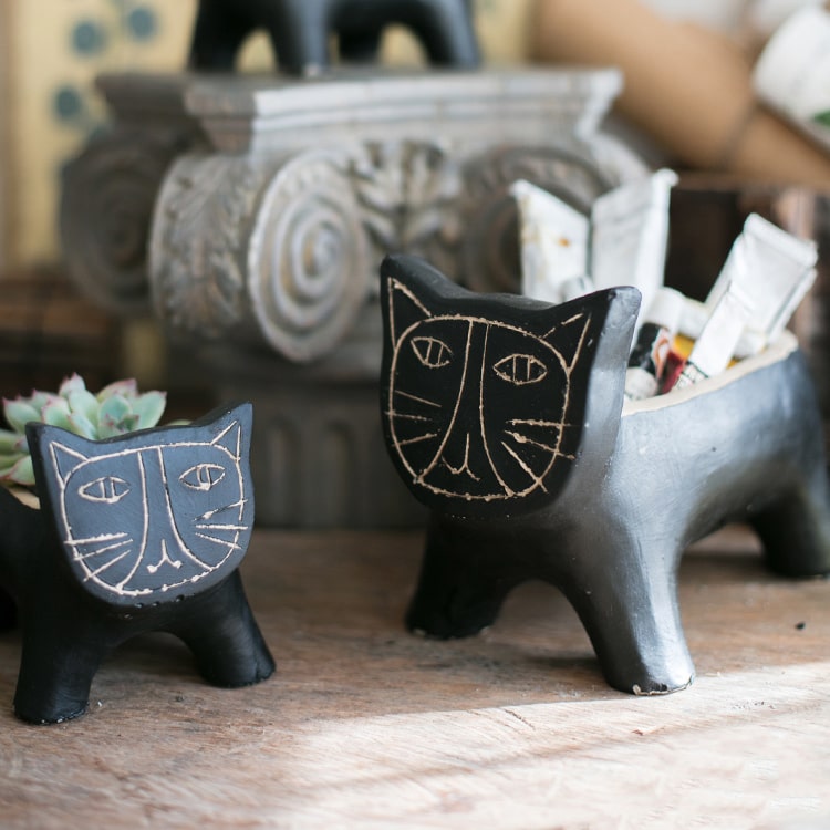 A charming cat-shaped small planter made of concrete, showcasing a unique design in black, khaki, and mixed colors.