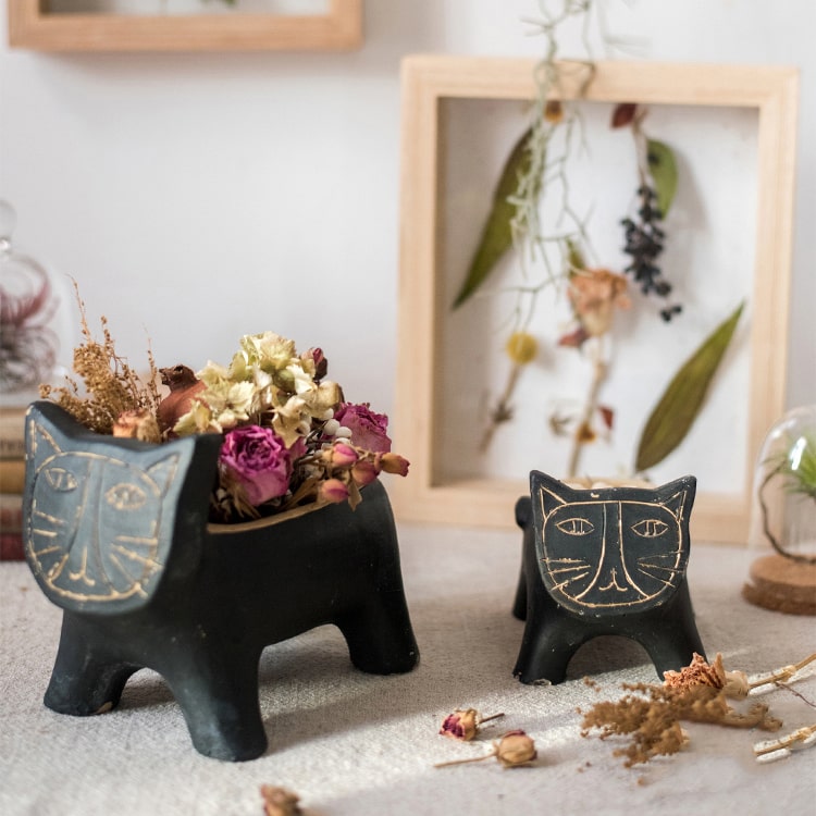 A charming cat-shaped small planter made of concrete, showcasing a unique design in black, khaki, and mixed colors.