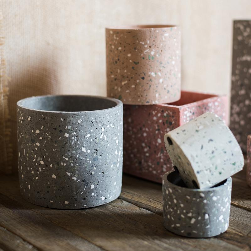 A collection of cement planters in various shapes, colors, and sizes, showcasing their modern design and durable material.