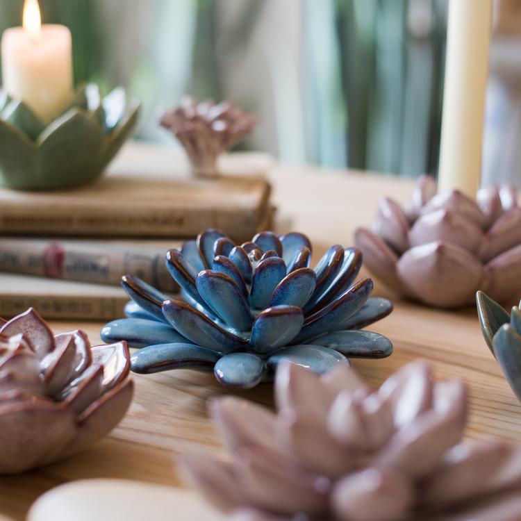 A collection of handmade ceramic floral table accents in various colors and sizes, showcasing their unique designs.