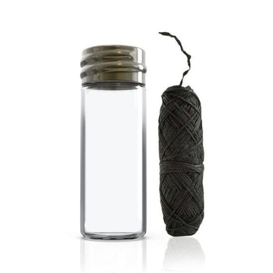 A glass bottle containing biodegradable charcoal dental floss, showcasing its eco-friendly packaging and spearmint flavor.