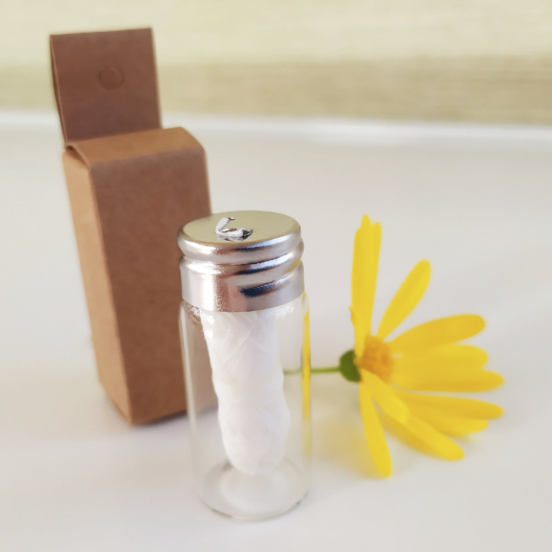 A glass bottle containing biodegradable charcoal dental floss, showcasing its eco-friendly packaging and spearmint flavor.