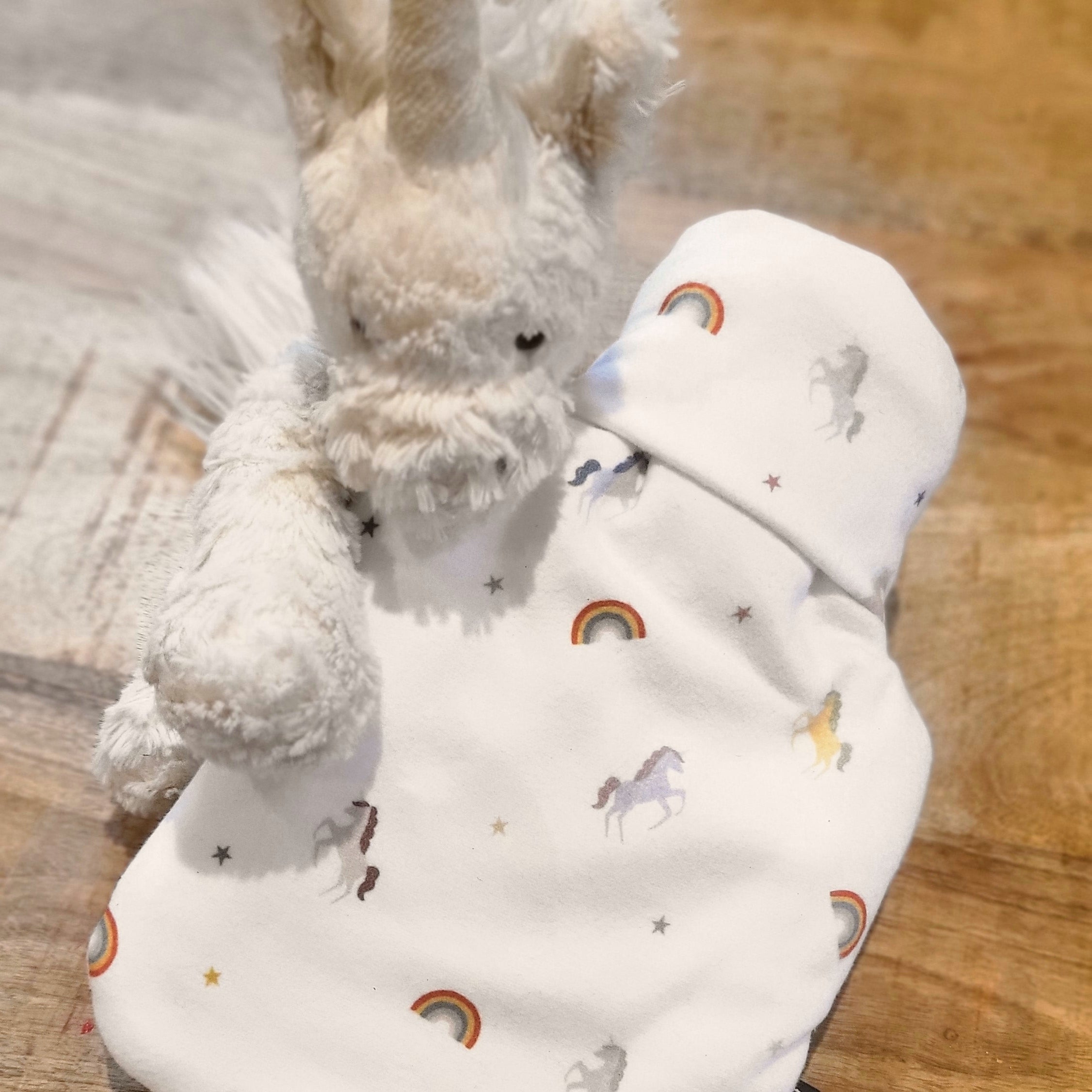 A soft children's hot water bottle featuring a colorful unicorn rainbow print, designed for comfort and safety.