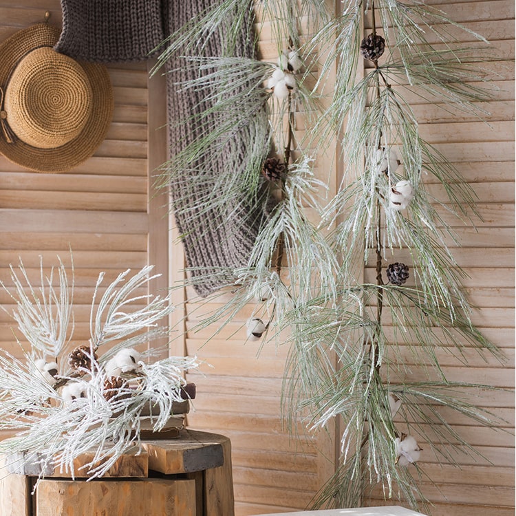 A beautifully crafted Christmas Faux Snow Pine Needle Wreath made from natural rattan, adorned with pine cones and cotton, showcasing a wintery aesthetic.