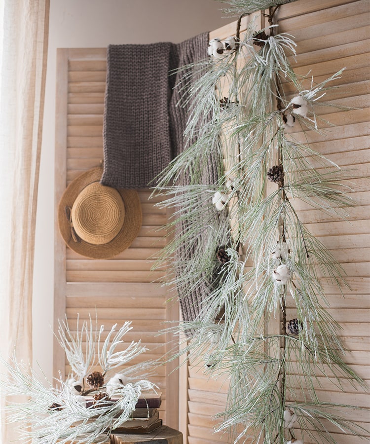 A beautifully crafted Christmas Faux Snow Pine Needle Wreath made from natural rattan, adorned with pine cones and cotton, showcasing a wintery aesthetic.