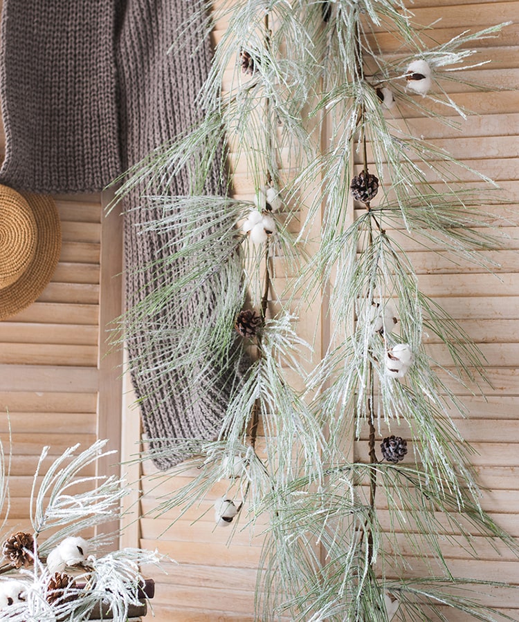 A beautifully crafted Christmas Faux Snow Pine Needle Wreath made from natural rattan, adorned with pine cones and cotton, showcasing a wintery aesthetic.