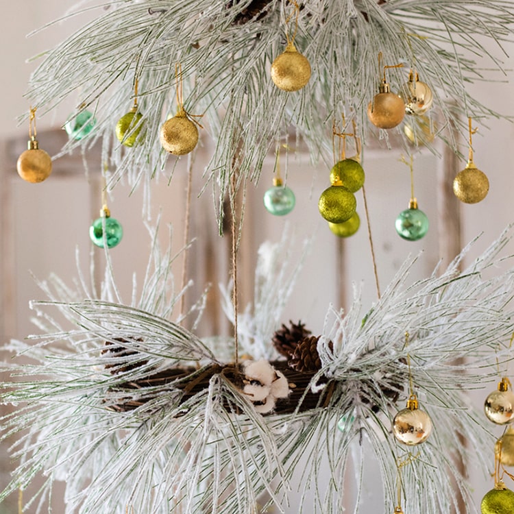 A beautifully crafted Christmas Faux Snow Pine Needle Wreath made from natural rattan, adorned with pine cones and cotton, showcasing a wintery aesthetic.