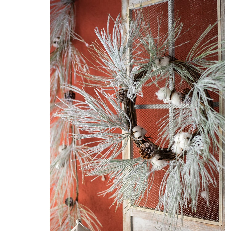 A beautifully crafted Christmas Faux Snow Pine Needle Wreath made from natural rattan, adorned with pine cones and cotton, showcasing a wintery aesthetic.