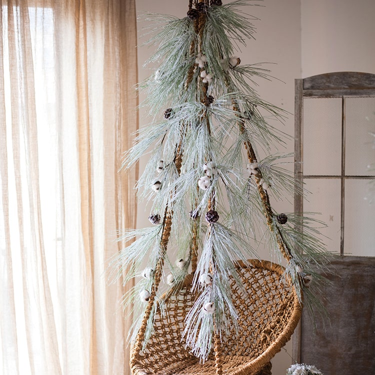 A beautifully crafted Christmas Faux Snow Pine Needle Wreath made from natural rattan, adorned with pine cones and cotton, showcasing a wintery aesthetic.