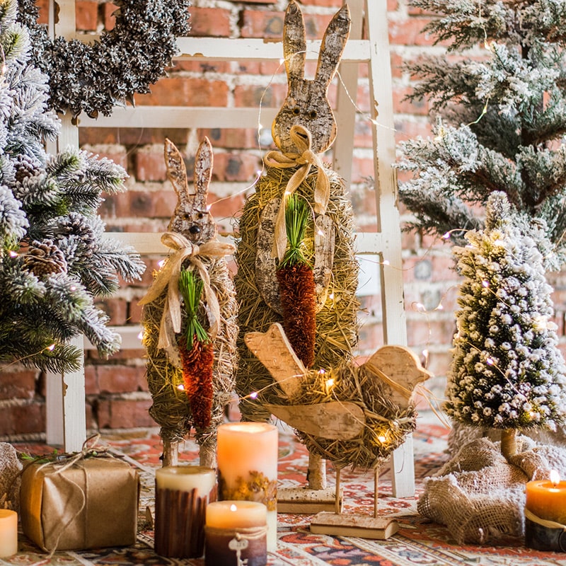 A collection of rustic Christmas figurine decorations including a hen, owl, rabbit, and flowers, crafted from natural wood and straw.