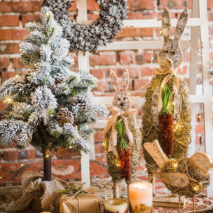 A collection of rustic Christmas figurine decorations including a hen, owl, rabbit, and flowers, crafted from natural wood and straw.