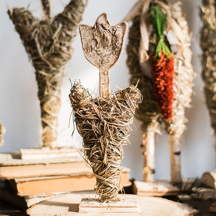 A collection of rustic Christmas figurine decorations including a hen, owl, rabbit, and flowers, crafted from natural wood and straw.