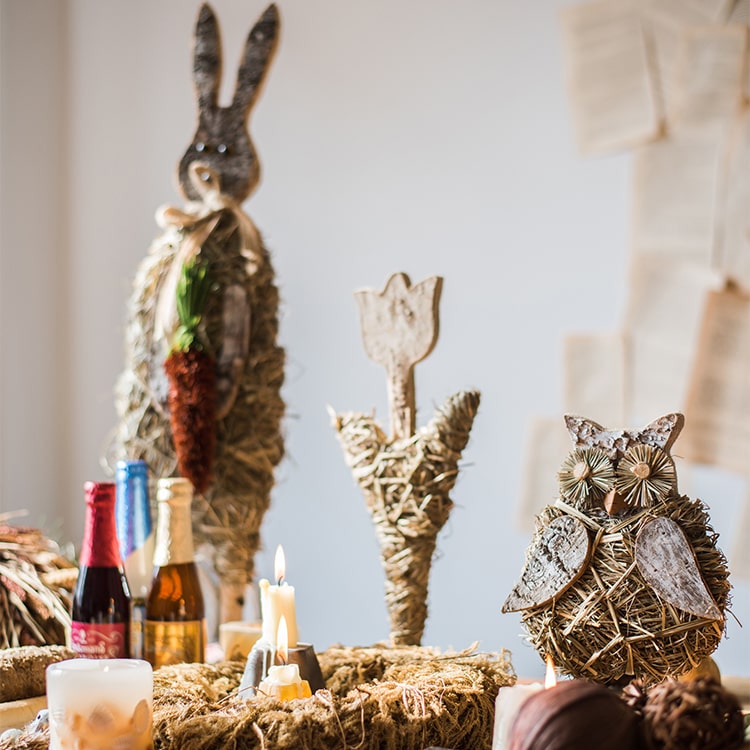 A collection of rustic Christmas figurine decorations including a hen, owl, rabbit, and flowers, crafted from natural wood and straw.