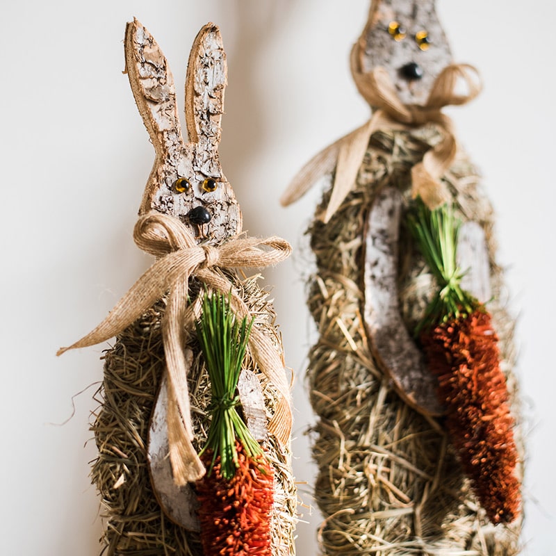 A collection of rustic Christmas figurine decorations including a hen, owl, rabbit, and flowers, crafted from natural wood and straw.