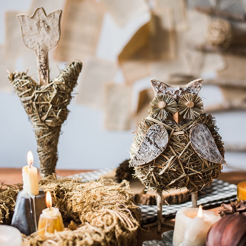 A collection of rustic Christmas figurine decorations including a hen, owl, rabbit, and flowers, crafted from natural wood and straw.