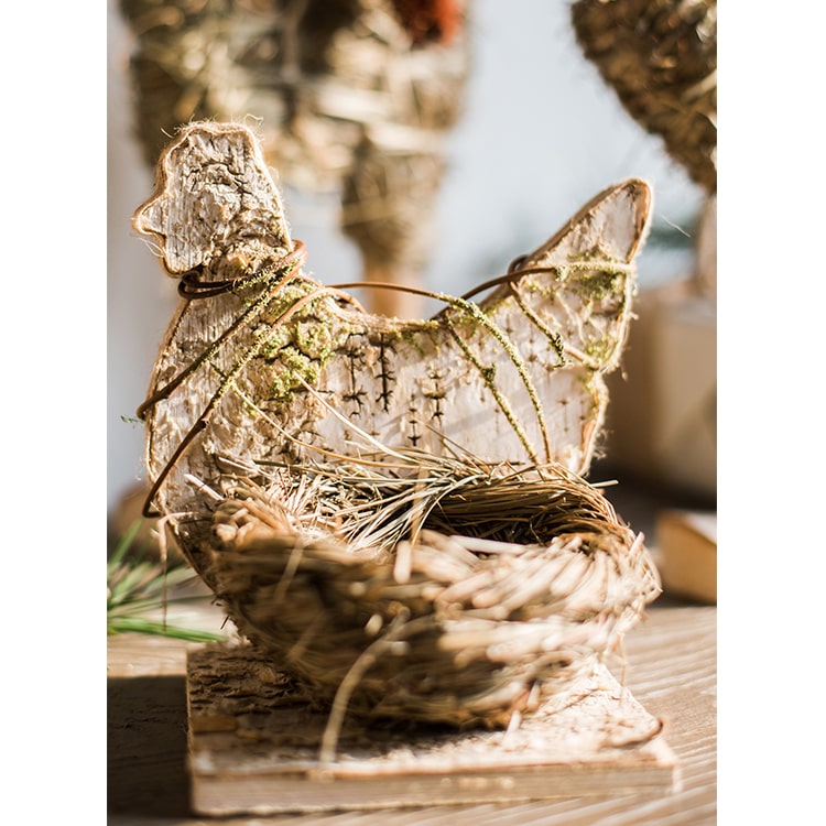 A collection of rustic Christmas figurine decorations including a hen, owl, rabbit, and flowers, crafted from natural wood and straw.