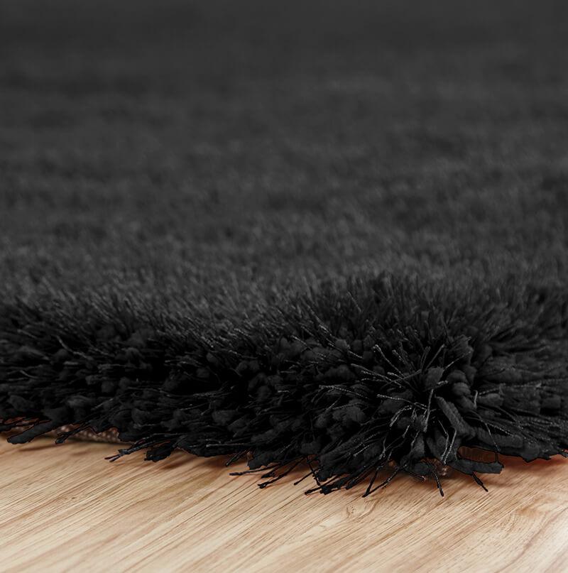 Chubby Black Area Rug featuring a soft shaggy texture, hand tufted design, and cotton backing, available in two sizes.