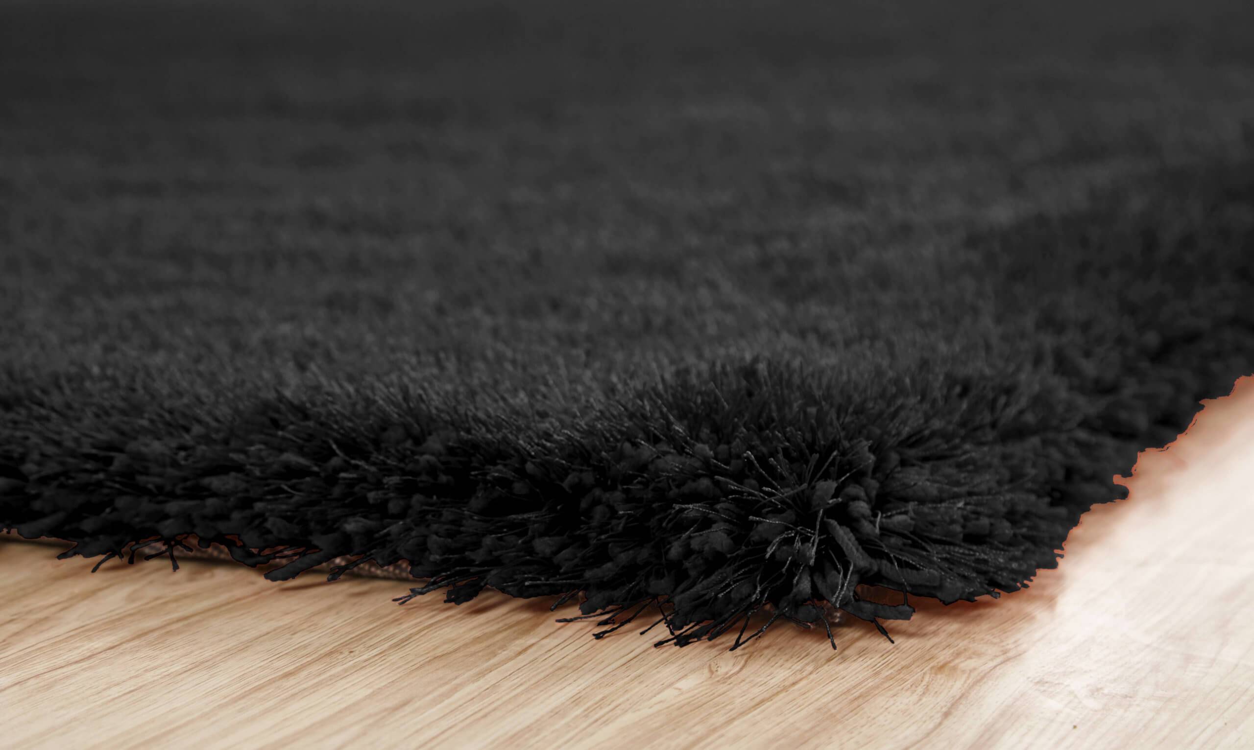 Chubby Black Area Rug featuring a soft shaggy texture, hand tufted design, and cotton backing, available in two sizes.