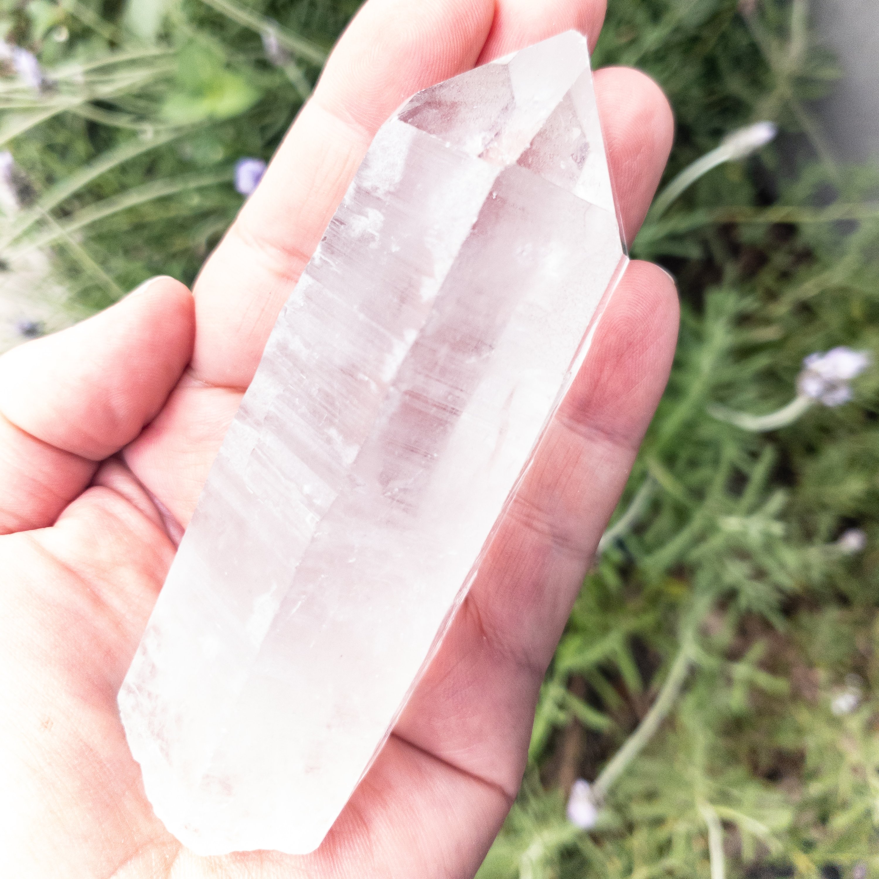 A single 5-inch long Crystal Quartz point, showcasing its clear, sparkling surface and natural shape, ideal for manifestation and cleansing other crystals.