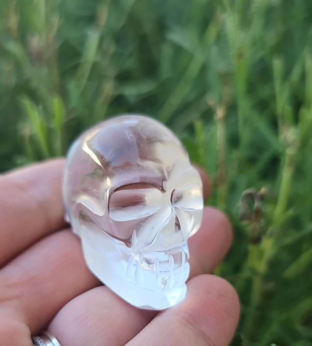 A beautifully handcrafted crystal skull made from high clarity quartz and amethyst, showcasing intricate details and vibrant colors.