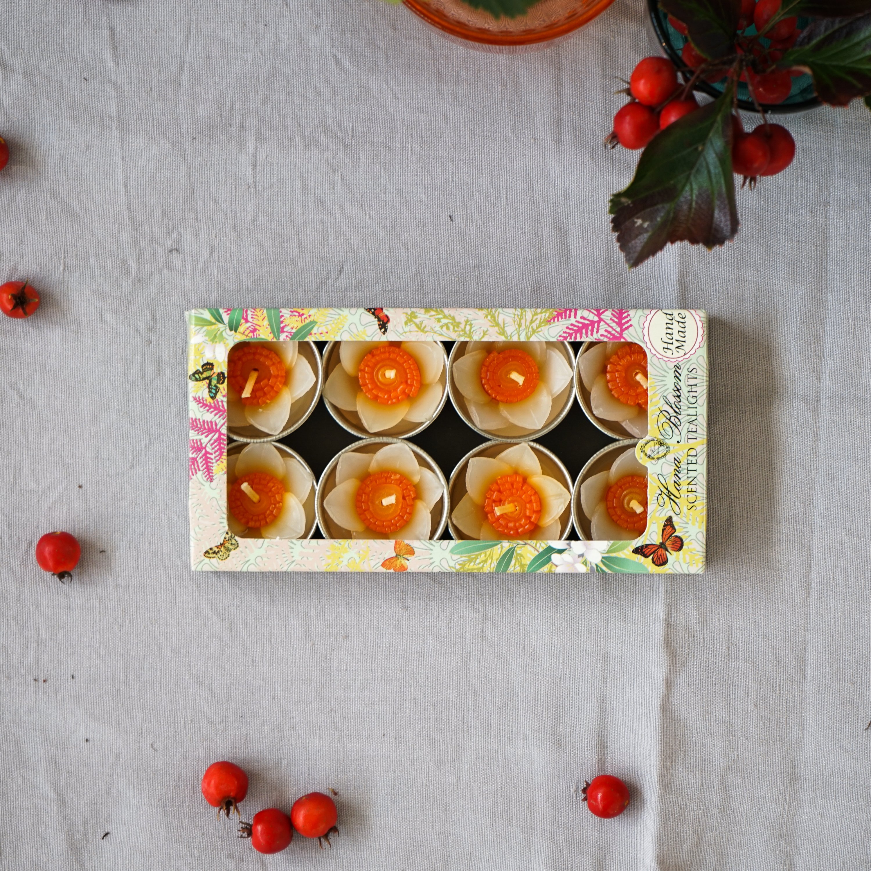 A set of eight handmade daffodil scented tealights in a decorative box, showcasing their floral design and vibrant colors.