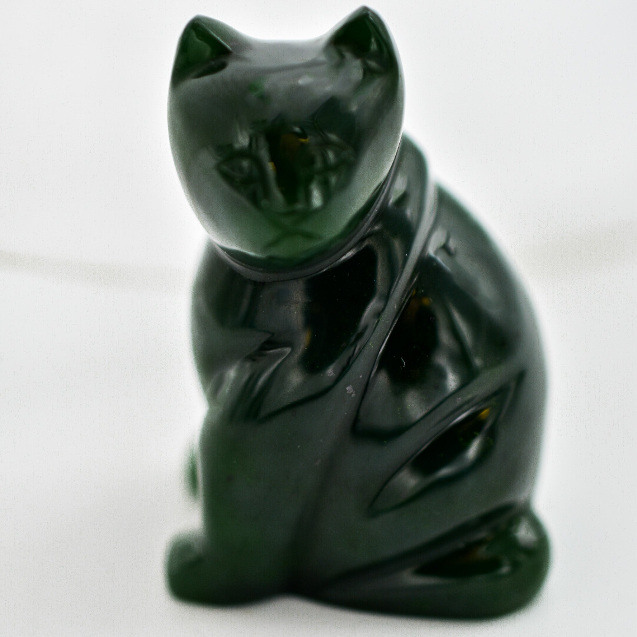 A beautifully hand-carved dark green jade cat figurine showcasing intricate details and unique patterns, symbolizing good luck and protection.