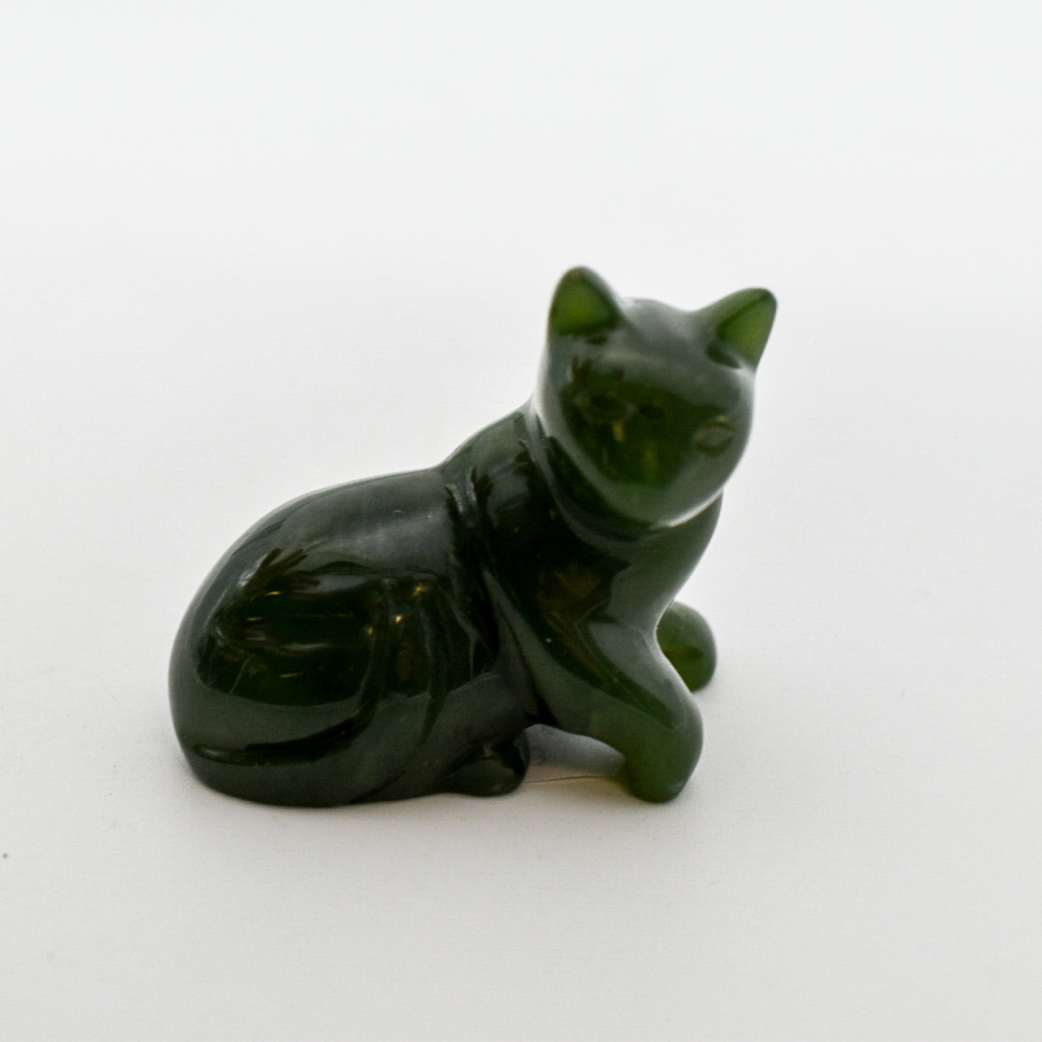 A beautifully hand-carved dark green jade cat figurine showcasing intricate details and unique patterns, symbolizing good luck and protection.