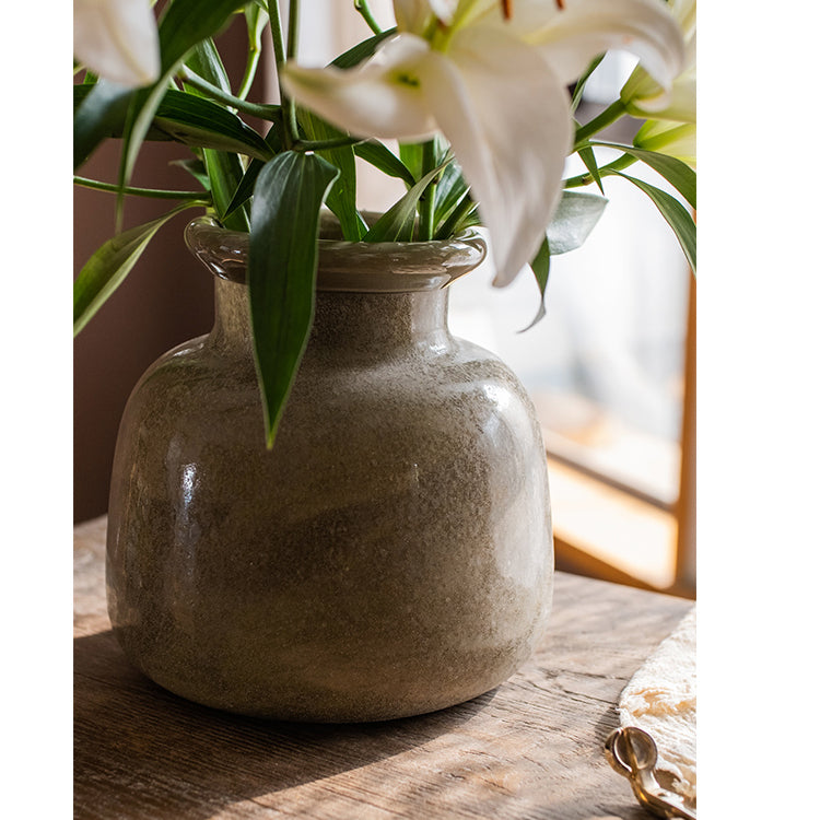 A dark green matte textured glass vase, hand-blown with a unique shape and finish, perfect for home decor.