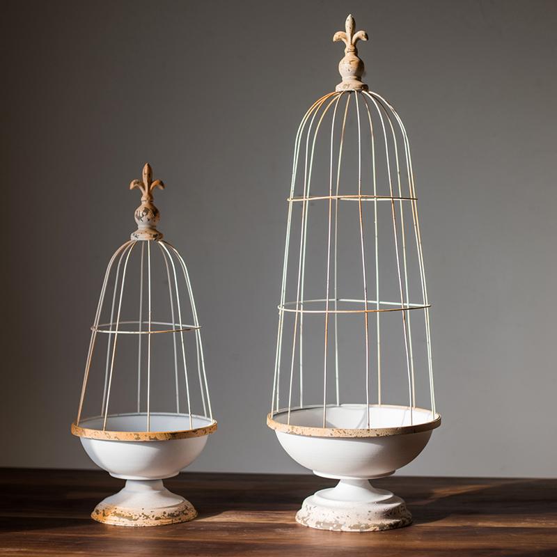 A decorative iron bird cage in white and rust colors, showcasing intricate designs and available in two sizes.