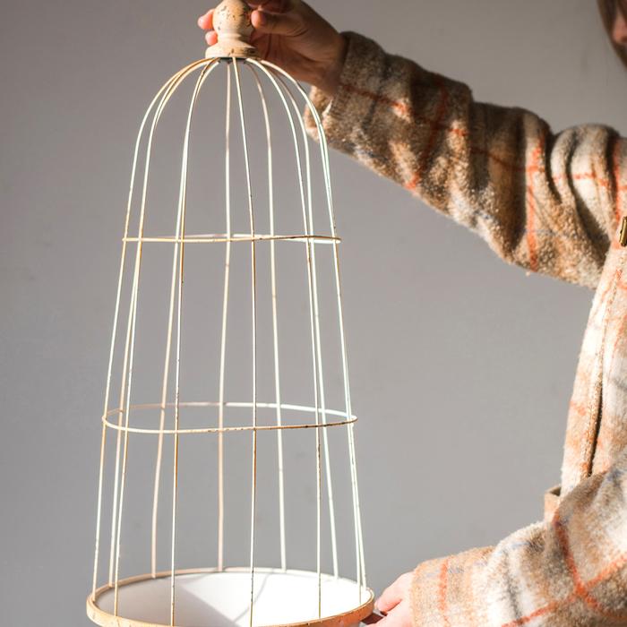 A decorative iron bird cage in white and rust colors, showcasing intricate designs and available in two sizes.