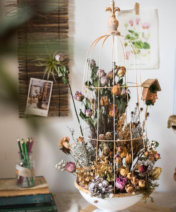 A decorative iron bird cage in white and rust colors, showcasing intricate designs and available in two sizes.