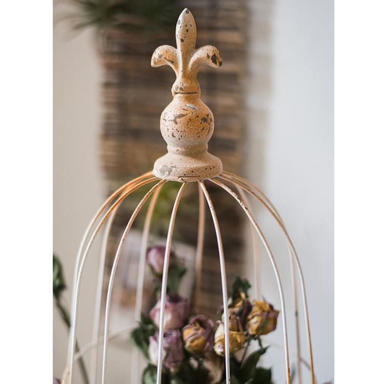 A decorative iron bird cage in white and rust colors, showcasing intricate designs and available in two sizes.