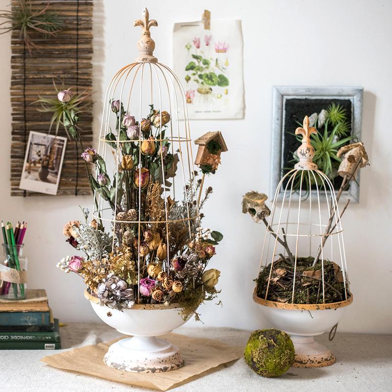 A decorative iron bird cage in white and rust colors, showcasing intricate designs and available in two sizes.