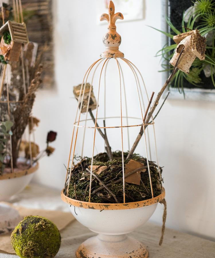 A decorative iron bird cage in white and rust colors, showcasing intricate designs and available in two sizes.