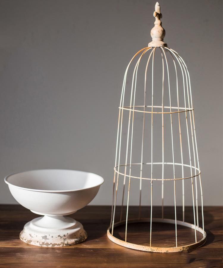 A decorative iron bird cage in white and rust colors, showcasing intricate designs and available in two sizes.