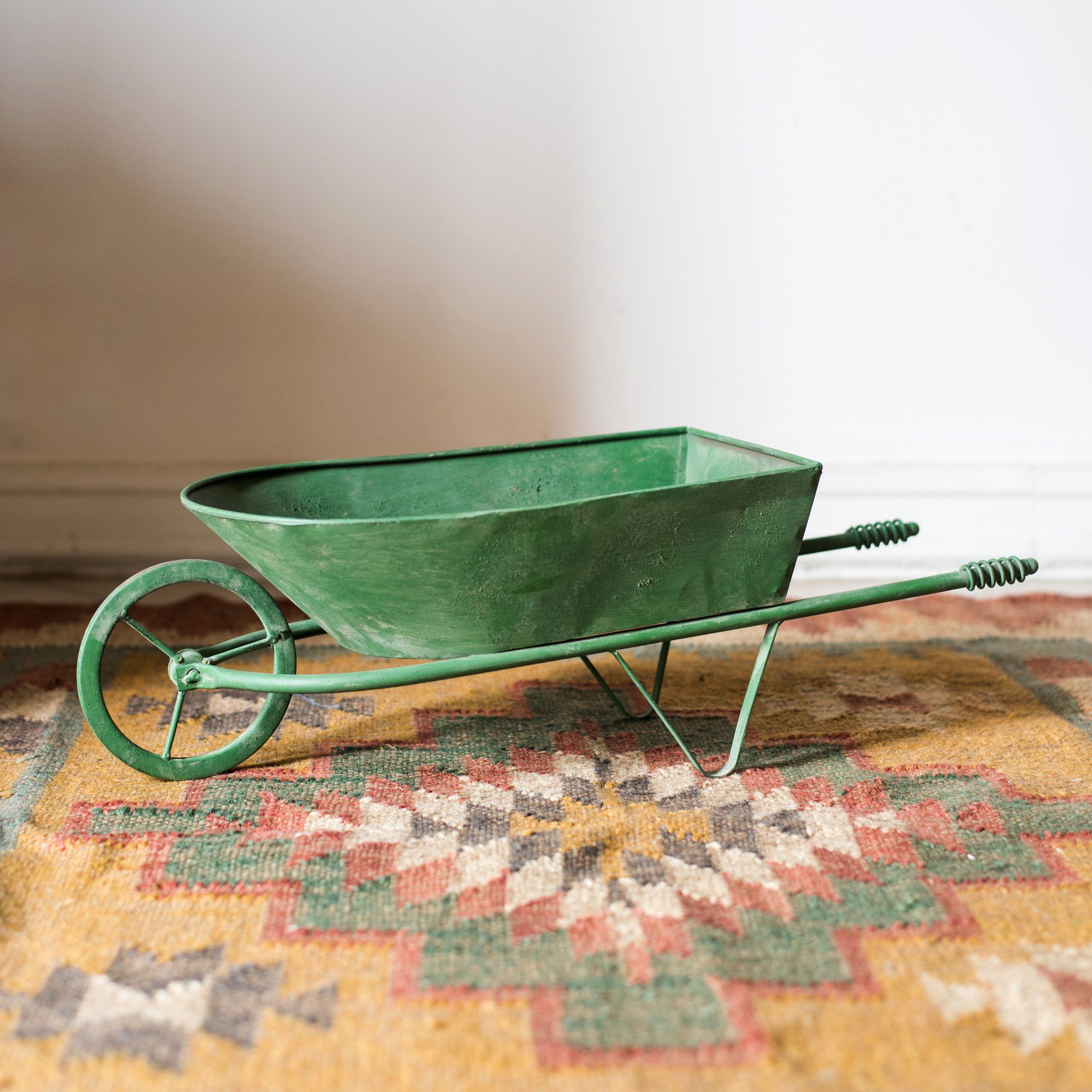 Decorative green metal planter cart showcasing plants, featuring wheels for easy mobility.