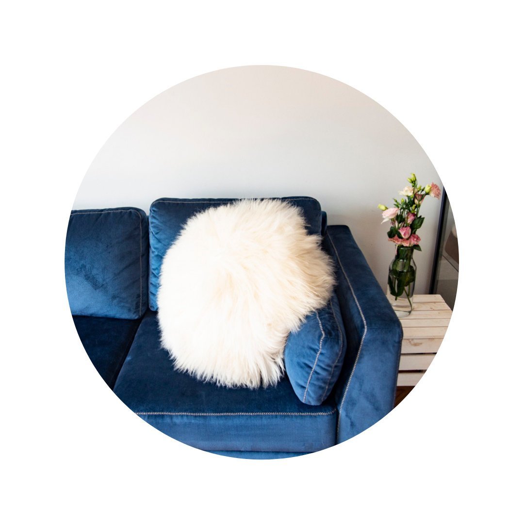 A decorative round furry pillow made from 100% natural sheepskin, showcasing its soft texture and luxurious appearance.