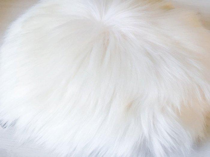 A decorative round furry pillow made from 100% natural sheepskin, showcasing its soft texture and luxurious appearance.