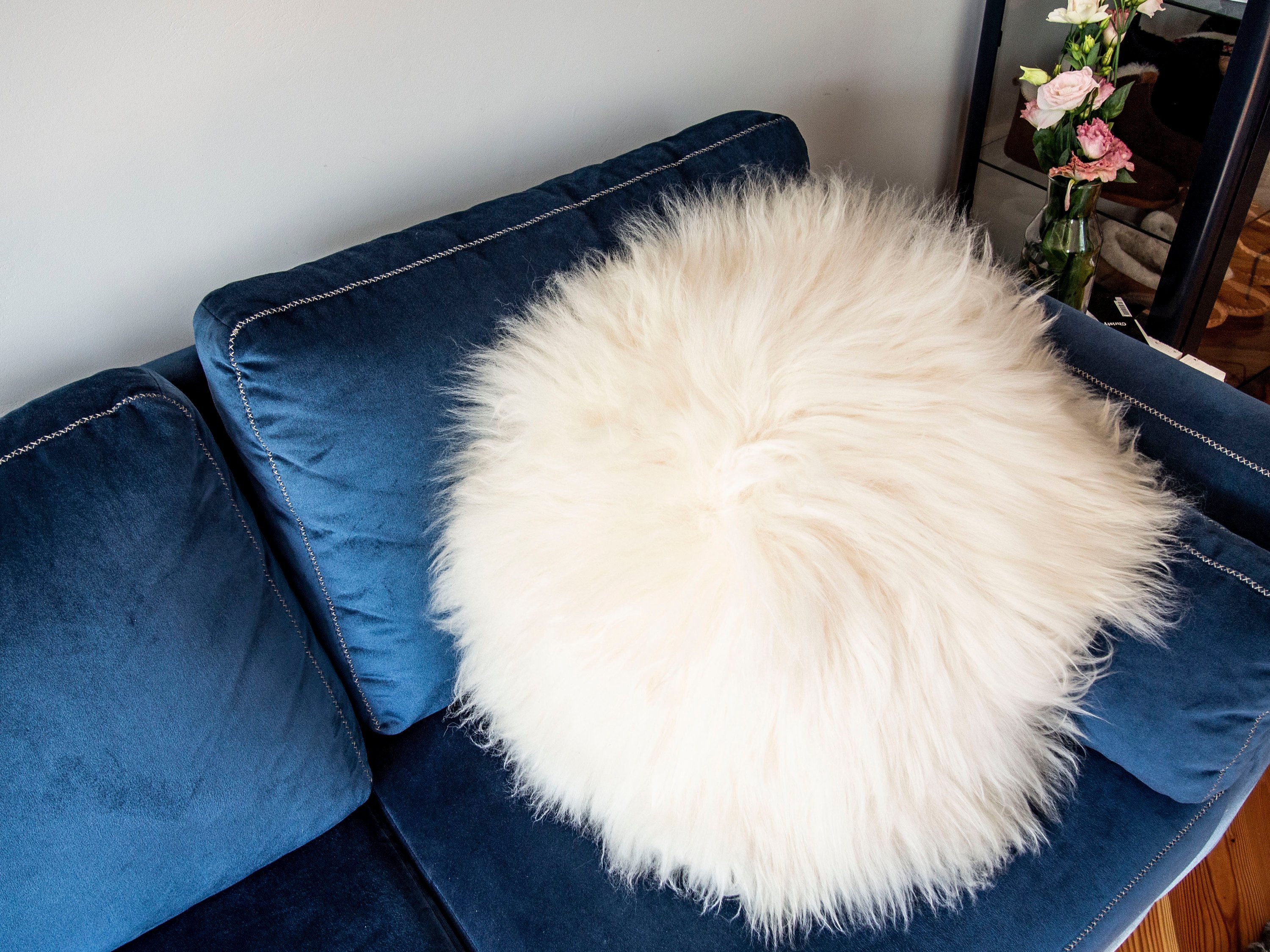 A decorative round furry pillow made from 100% natural sheepskin, showcasing its soft texture and luxurious appearance.