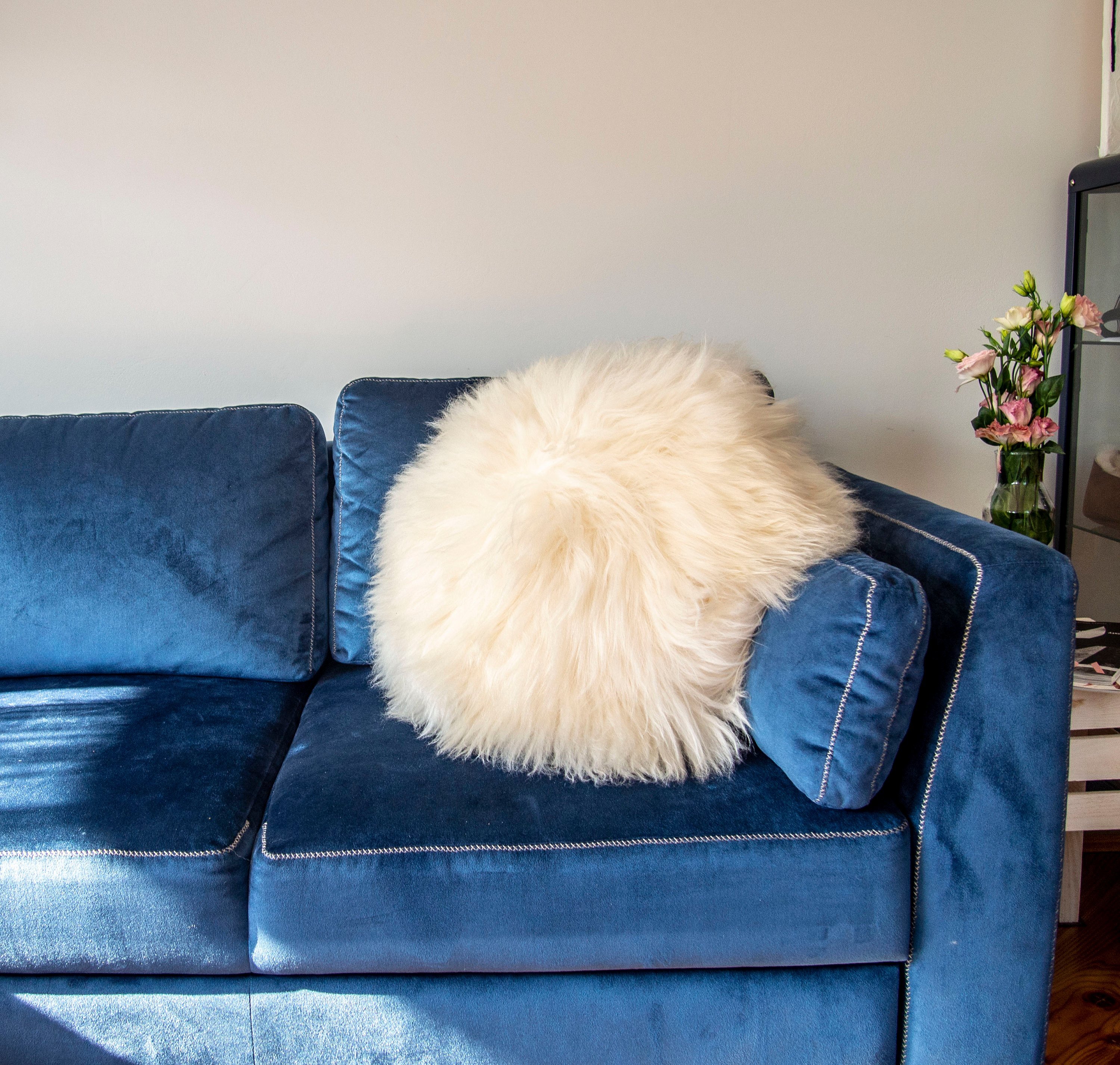 A decorative round furry pillow made from 100% natural sheepskin, showcasing its soft texture and luxurious appearance.