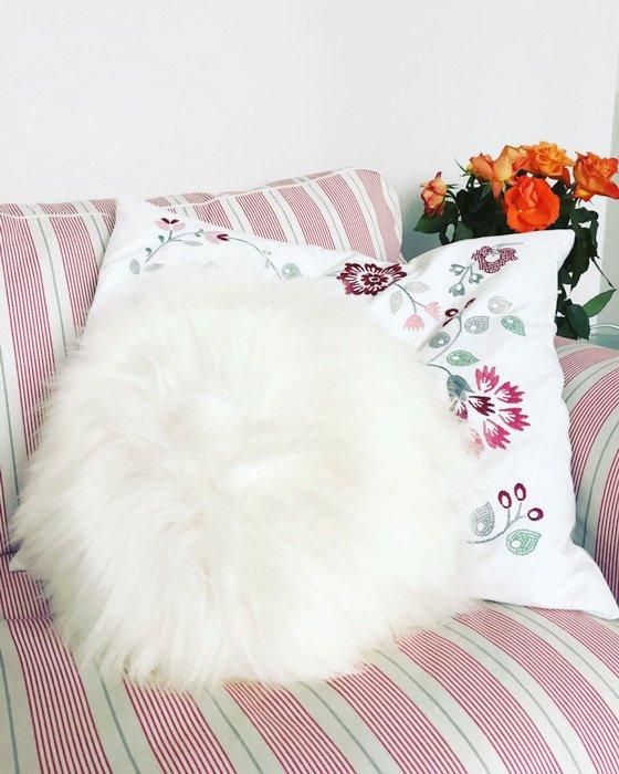 A decorative round furry pillow made from 100% natural sheepskin, showcasing its soft texture and luxurious appearance.