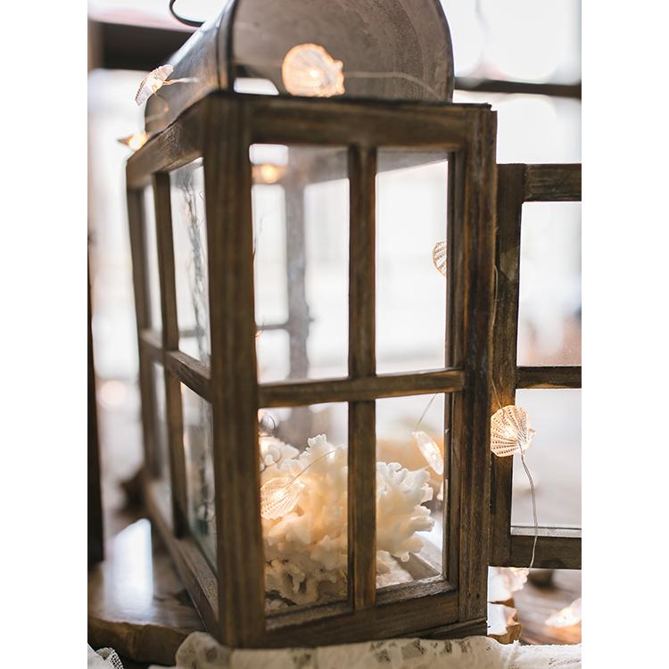 A beautifully crafted decorative table lantern made of wood and glass, featuring a rustic design with a candle inside, perfect for home decor.