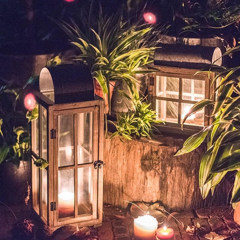 A beautifully crafted decorative table lantern made of wood and glass, featuring a rustic design with a candle inside, perfect for home decor.