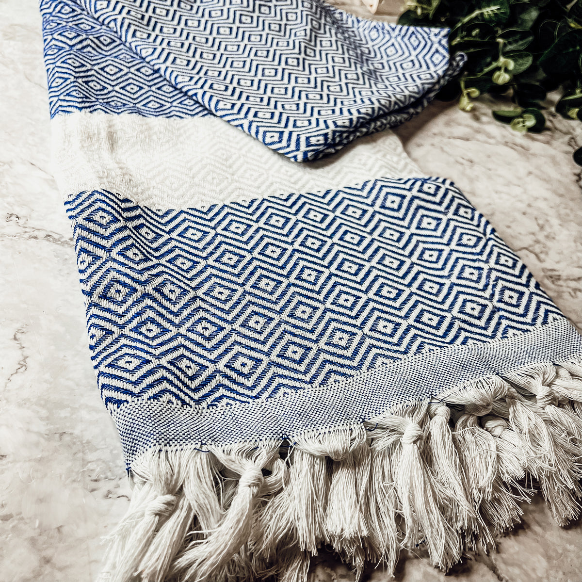 A luxurious Diamond Towel 200GSM in blue with decorative tassels, showcasing its oversized design and unique diamond pattern.