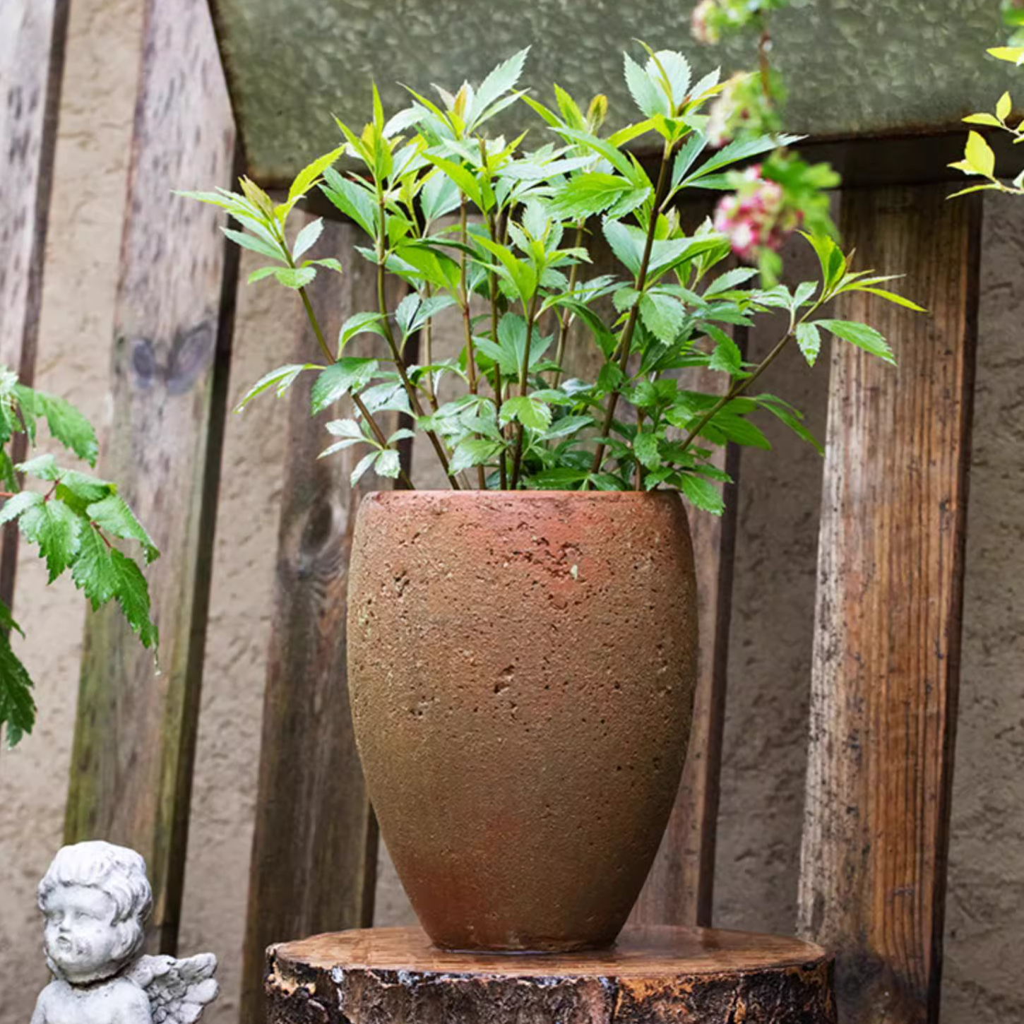 Tall distressed cement plant pot in terracotta color, showcasing a rustic design suitable for indoor and outdoor use.