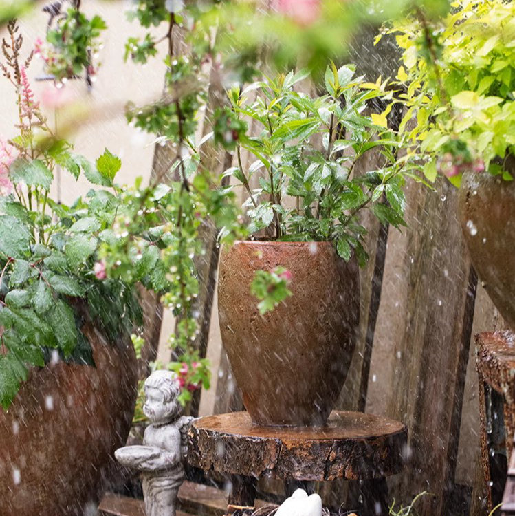 Tall distressed cement plant pot in terracotta color, showcasing a rustic design suitable for indoor and outdoor use.