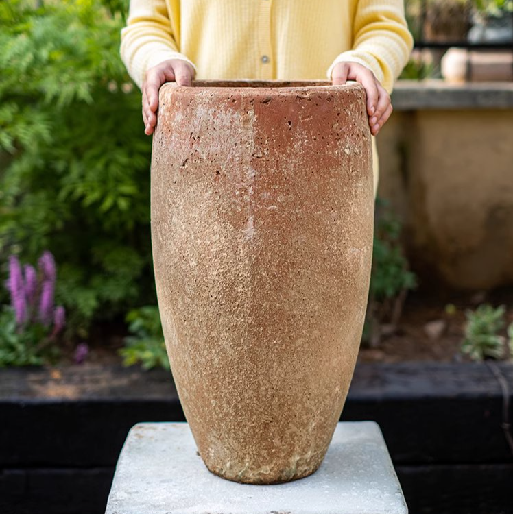 Tall distressed cement plant pot in terracotta color, showcasing a rustic design suitable for indoor and outdoor use.