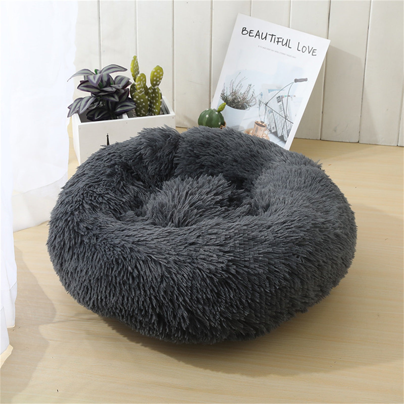 A dark gray plush round dog bed designed for comfort, featuring faux shag fur and a cozy nest shape for pets to snuggle into.