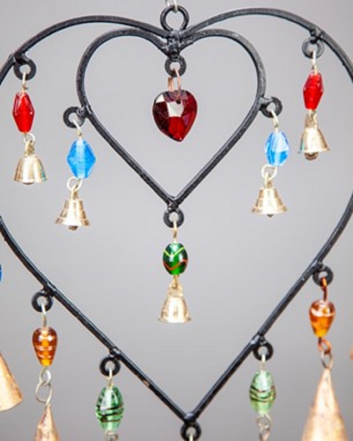 A colorful double heart design hanging chime made of glass beads and brass bells, showcasing vibrant colors and intricate craftsmanship.